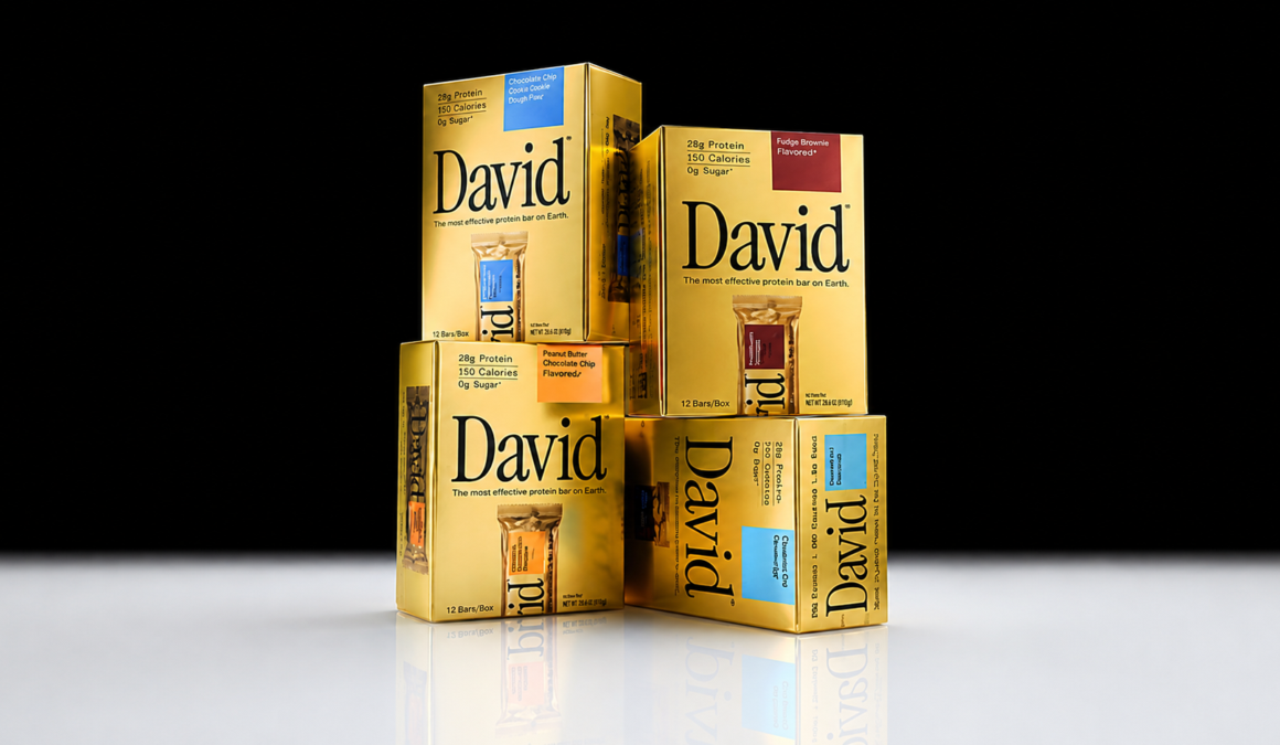 Gold cardboard boxes of David protein bars stacked against a dark background, each printed with 28g Protein, 150 Calories and 0g Sugar