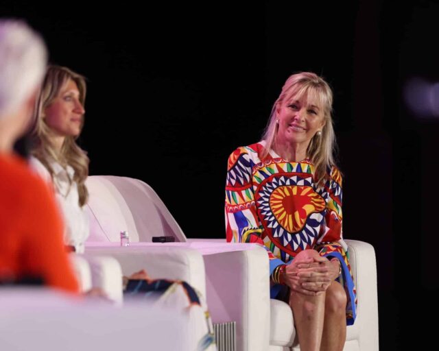 Three speakers seated in armchairs on stage at the Global Wellness Summit.