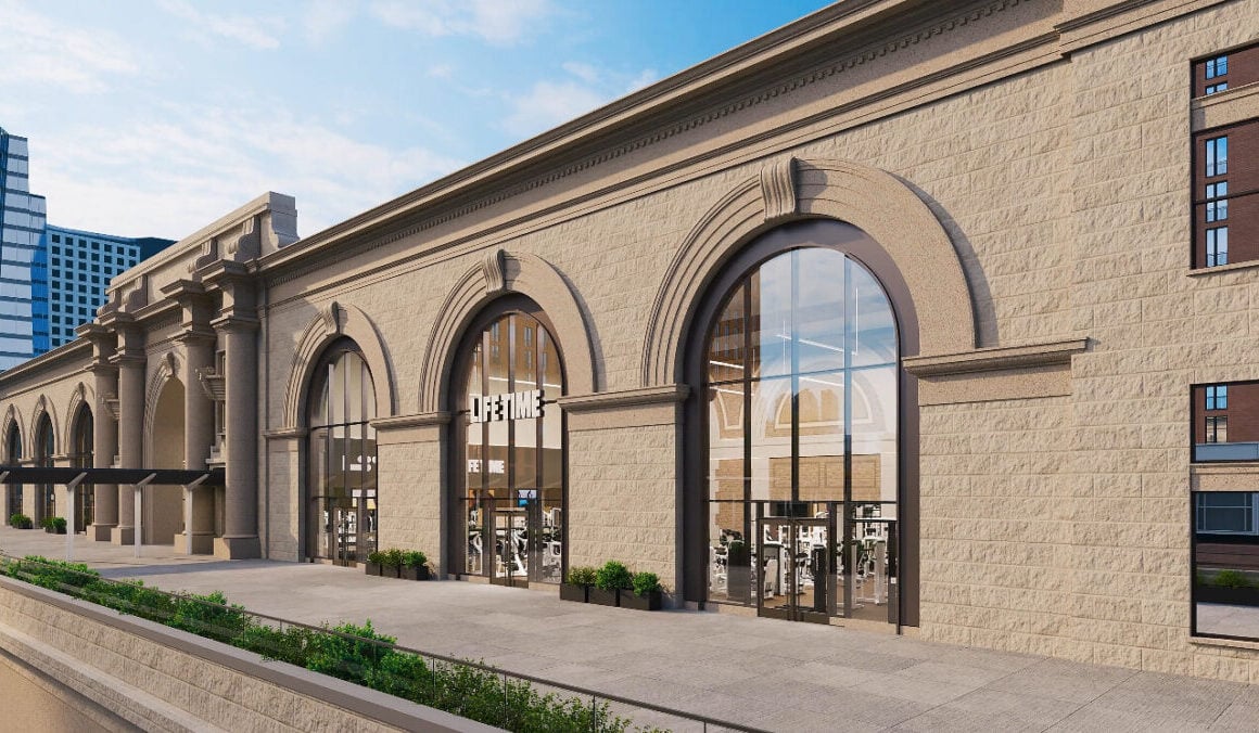 Rendering of the planned Life Time club inside Commonwealth Pier's stone facade in Boston's Seaport, with tall arched glass windows showing gym equipment inside