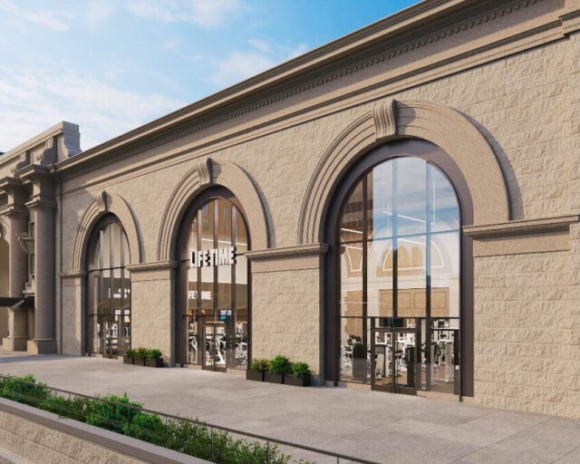 Rendering of the planned Life Time club inside Commonwealth Pier's stone facade in Boston's Seaport, with tall arched glass windows showing gym equipment inside